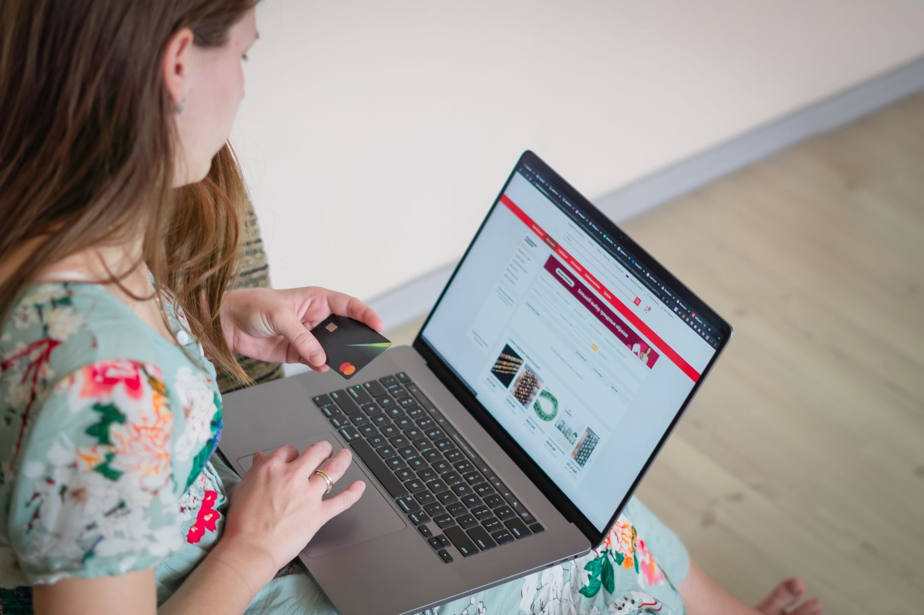 Personne faisant un achat en ligne sur son ordinateur portable, carte bancaire en main