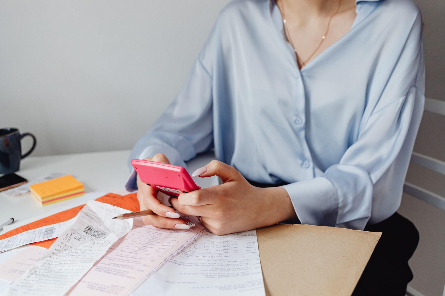 Personne calculant un budget avec calculatrice et factures