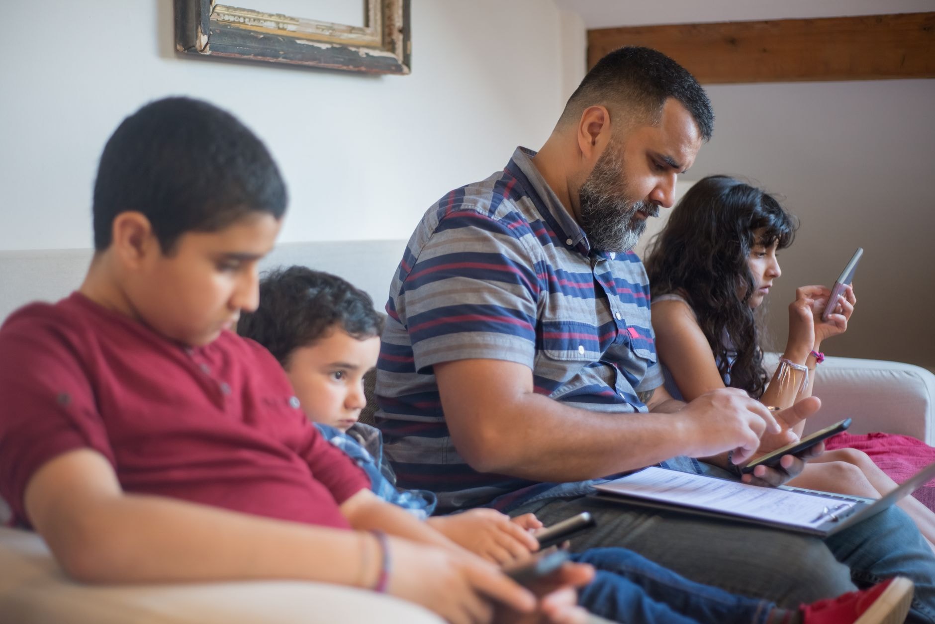 Famille utilisant plusieurs appareils connectés sur un canapé